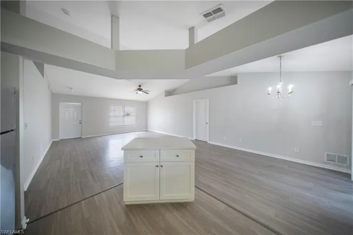Unfurnished living room with light wood-style floors, a ceiling fan, and a chandelier