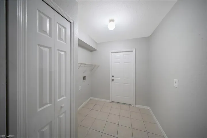 Laundry area featuring light tile patterned floors, a textured ceiling, and washer hookup