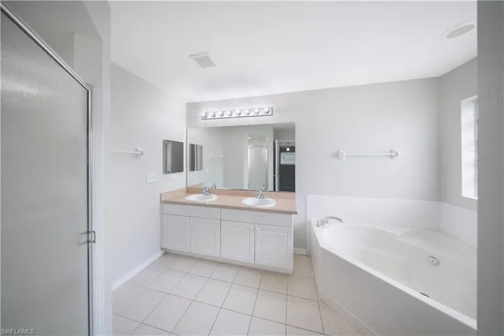 Full bath with light tile patterned floors, a bath, double vanity, and a shower stall