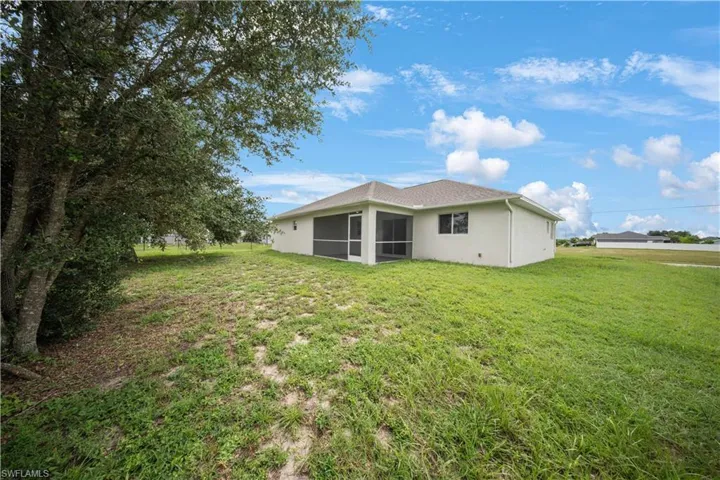 Back of property with a yard, a sunroom, and stucco siding