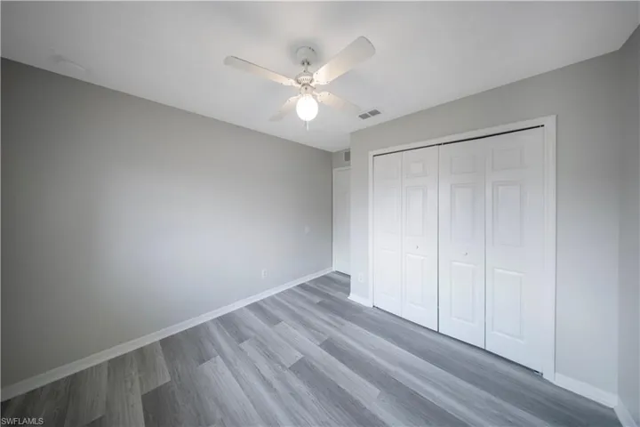 Unfurnished bedroom with wood finished floors, a closet, and a ceiling fan