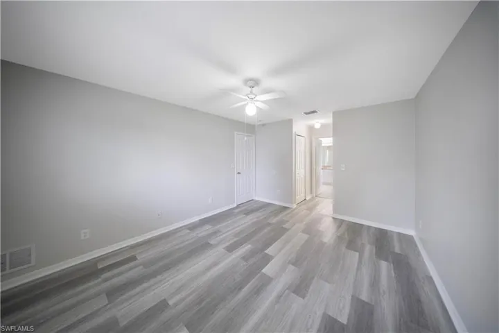 Unfurnished bedroom with light wood-style flooring, a closet, connected bathroom, and a ceiling fan