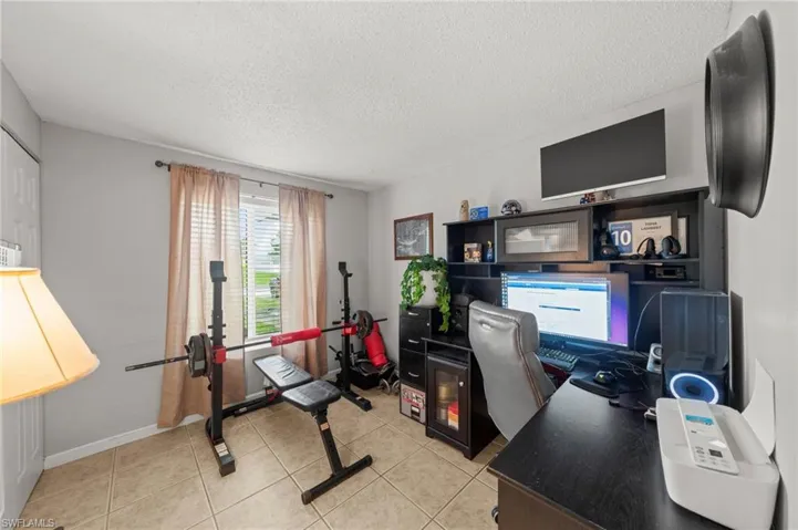 Home office with light tile patterned floors and a textured ceiling