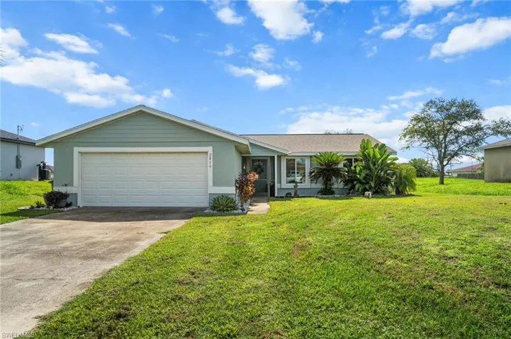 Ranch-style home with concrete driveway, an attached garage, and a front lawn