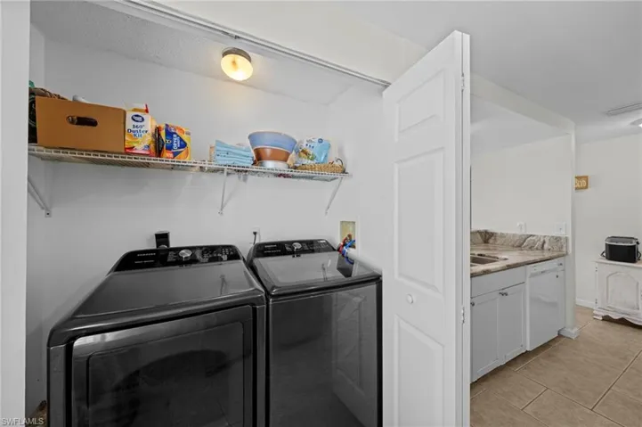 Laundry room featuring washing machine and clothes dryer and light tile patterned floors