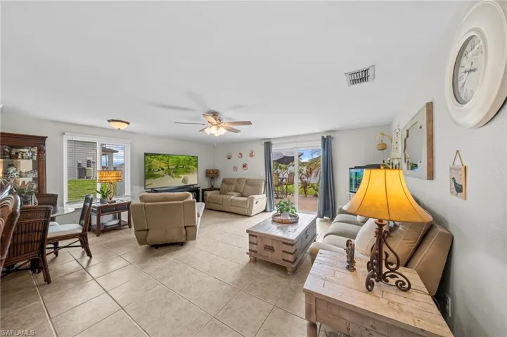 Living area with a ceiling fan, light tile patterned floors, and healthy amount of natural light