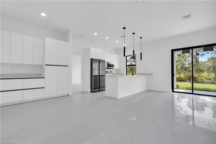 Unfurnished living room featuring healthy amount of natural light, recessed lighting, light marble finish flooring, and a sink