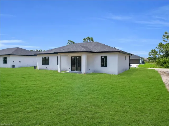 Back of property featuring stucco siding and a lawn