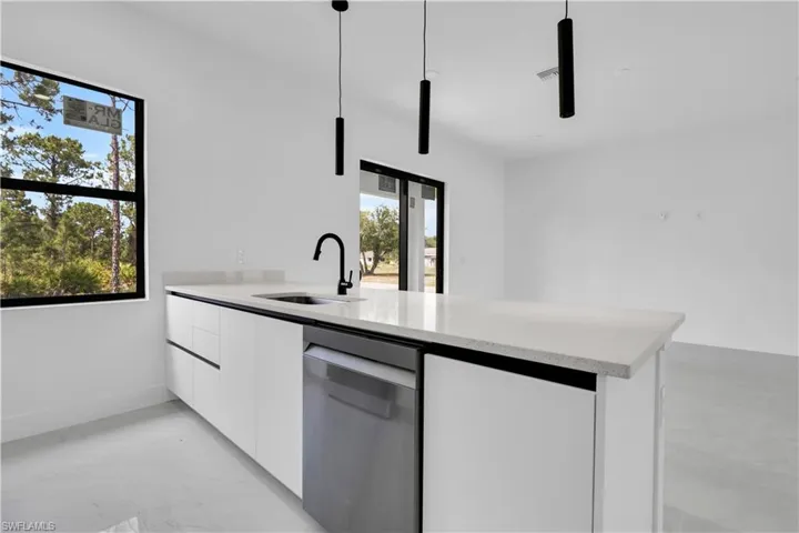 Kitchen with a sink, stainless steel dishwasher, modern cabinets, white cabinetry, and a peninsula