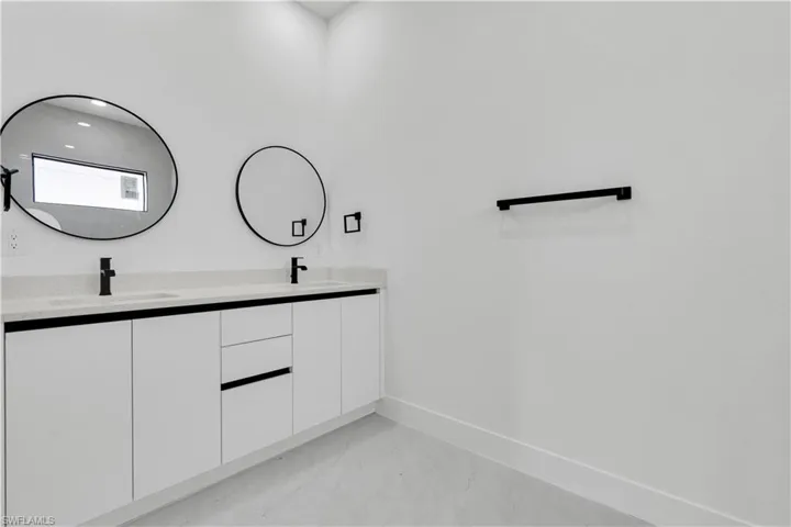 Full bathroom with double vanity, marble finish flooring, baseboards, and recessed lighting