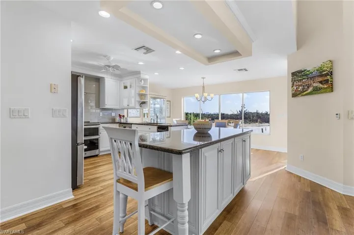 Kitchen featuring light hardwood / wood-style floors, white cabinetry, backsplash, and a tray ceiling