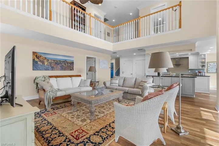 The great room area features a light, wood-look flooring throughout,  a soaring ceiling that opens to the top floor, and a fabulous wrap-around lanai with sliding doors, filling the home with tons of natural light.