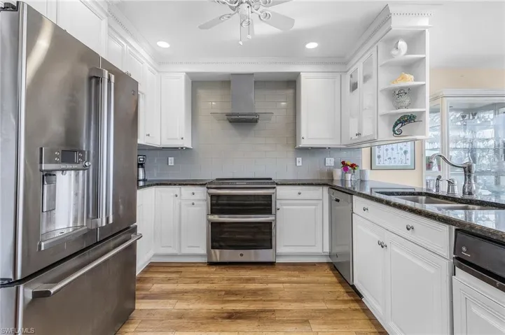 Light and Bright, Gorgeous Kitchen with appliances with stainless steel finishes, glass tile backsplash, stainless steal sink, and wall chimney exhaust hood.