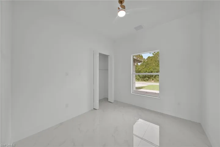 Unfurnished bedroom featuring marble tiled floors, ceiling fan, and a closet