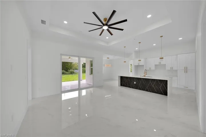 Unfurnished living room featuring light marble finish flooring, a tray ceiling, ceiling fan, and recessed lighting