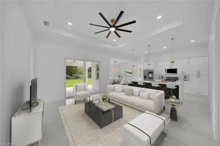 Living area featuring a raised ceiling, a ceiling fan, and recessed lighting