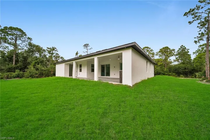 Back of property featuring stucco siding, a patio, and a lawn