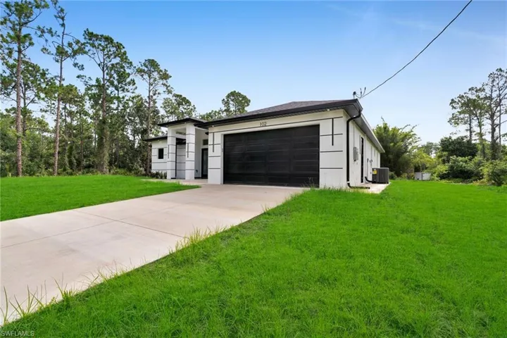 View of front of property featuring driveway, an attached garage, a front lawn, and stucco siding