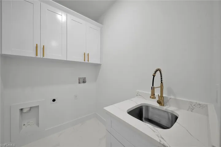 Laundry area with cabinet space, hookup for a washing machine, hookup for an electric dryer, and marble finish flooring