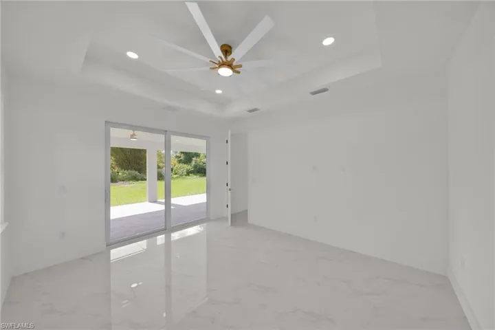 Spare room featuring a tray ceiling, light marble finish flooring, a ceiling fan, and recessed lighting