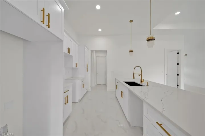 Kitchen with light marble finish floors, recessed lighting, light stone countertops, white cabinetry, and decorative light fixtures