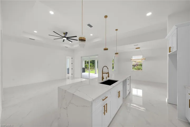 Kitchen with light marble finish floors, recessed lighting, a tray ceiling, white cabinets, and open floor plan