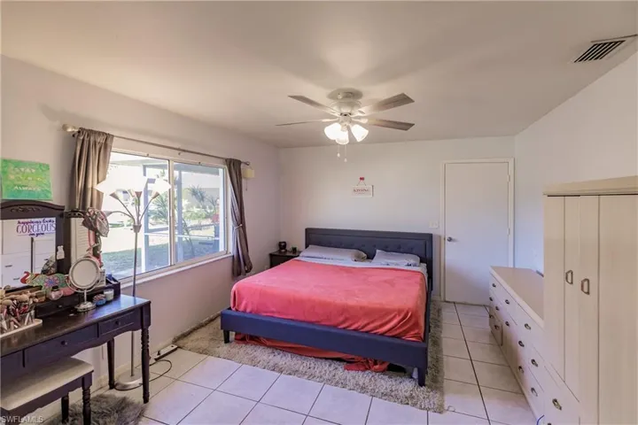 Tiled bedroom featuring ceiling fan