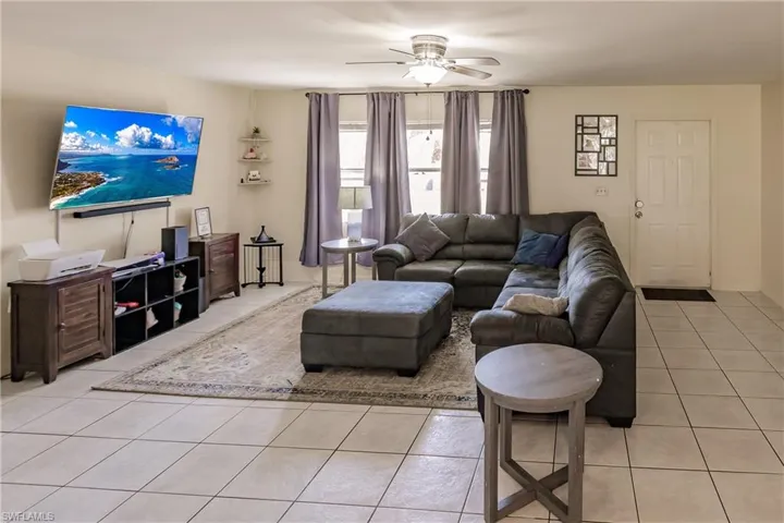 Living room with ceiling fan and light tile patterned flooring