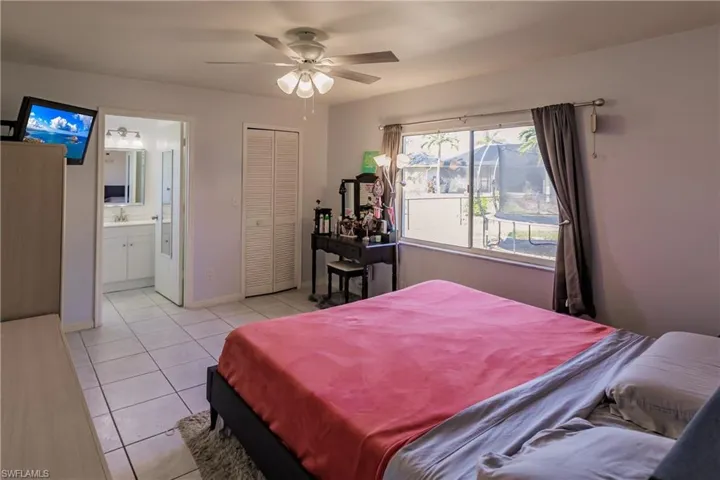 Bedroom featuring ceiling fan, light tile patterned flooring, a closet, and ensuite bath