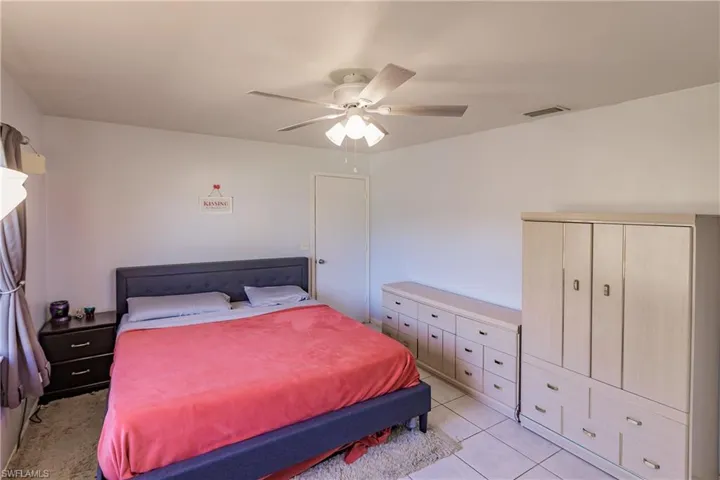 Tiled bedroom with ceiling fan and a closet