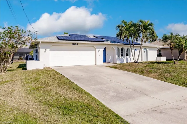 Ranch-style house with a front yard, solar panels, and a garage