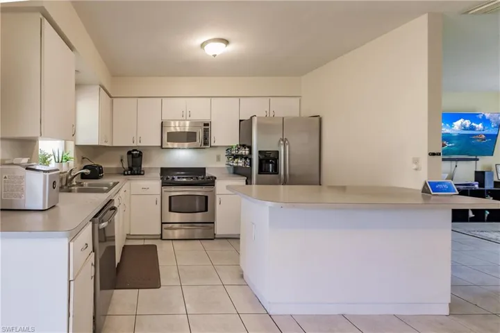 Kitchen with white cabinetry, sink, light tile patterned floors, and appliances with stainless steel finishes