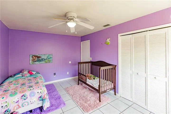 Tiled bedroom with ceiling fan and a closet