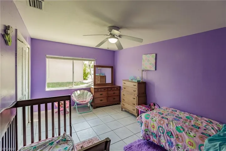 Tiled bedroom featuring ceiling fan and a closet