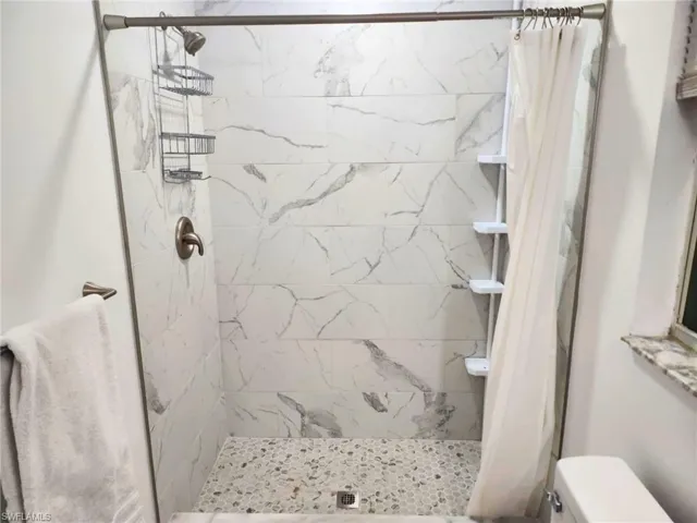 Bathroom featuring a shower with shower curtain and toilet