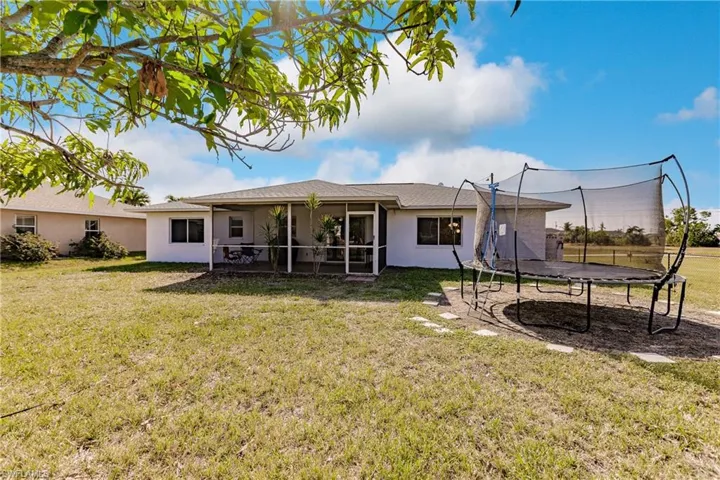 Back of property with a yard and a trampoline