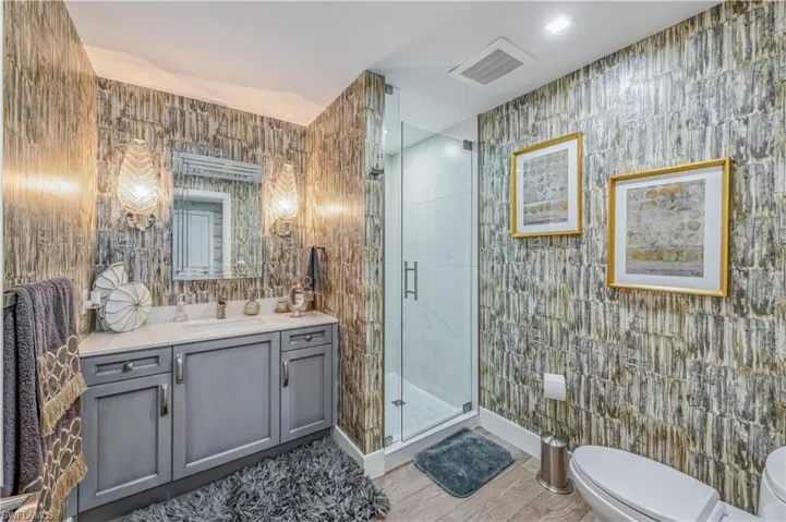 Bathroom with vanity, a stall shower, wallpapered walls, and light wood finished floors