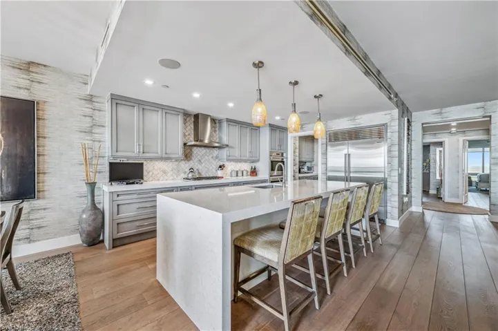 Kitchen featuring gray cabinetry, a kitchen bar, light stone countertops, and stainless steel appliances
