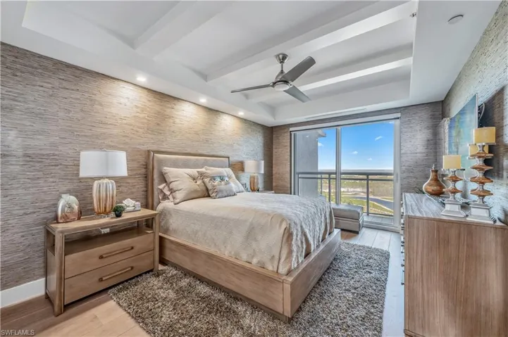 Bedroom featuring access to exterior, beamed ceiling, and a tray ceiling