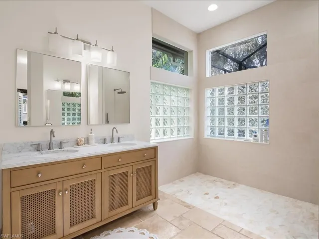 Bathroom featuring double vanity, stone tile floors, and a shower