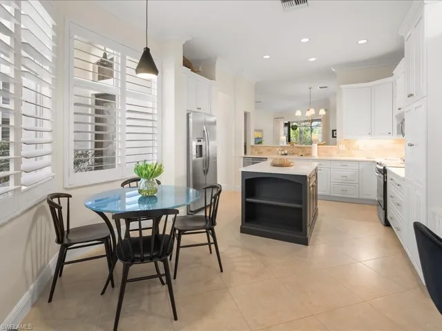 Kitchen featuring pendant lighting, ornamental molding, open shelves, a center island, and dual tone cabinets