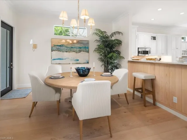 Dining space with ornamental molding, light wood-style flooring, and suspended lighting
