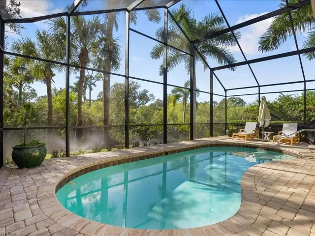 Outdoor pool featuring a sunroom, glass enclosure, and a patio area