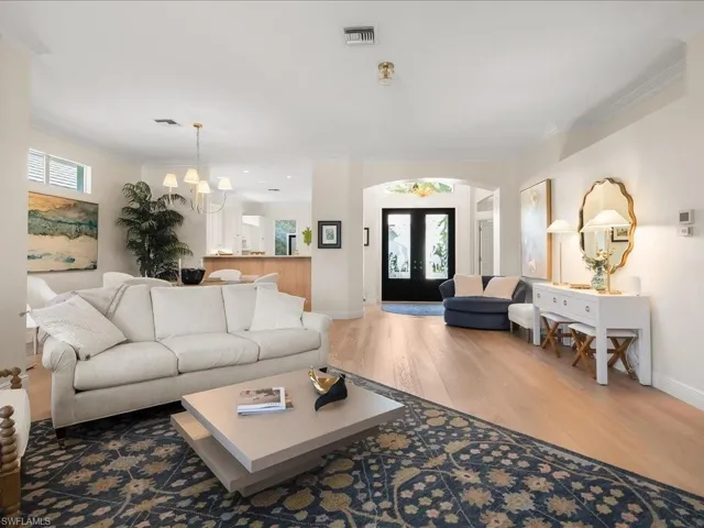 Living room featuring crown molding, wood finished floors, french doors, plenty of natural light, and suspended lighting