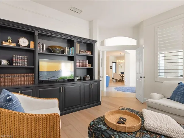 Living room featuring light wood-type flooring, arched walkways, and built in shelves