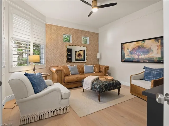 Living room featuring an accent wall, wood finished floors, ceiling fan, and wallpapered walls