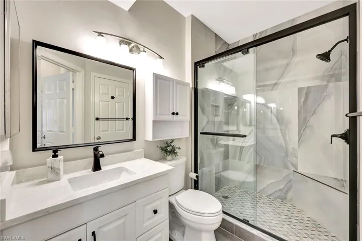 Modern bathroom featuring a glass-enclosed shower with large format wall tiles, a built-in shower bench, and a geometric floor tile pattern
