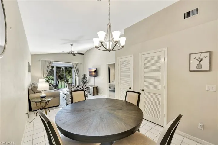 Dining area featuring a contemporary five-light chandelier, a round wood-finish table, and tile flooring