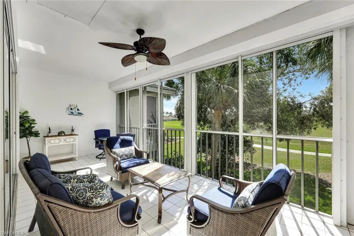 Enclosed lanai featuring a ceiling fan, tiled flooring, and screened panels offering outdoor scenery