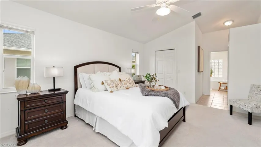 Bedroom with light carpet, a closet, vaulted ceiling, and a ceiling fan